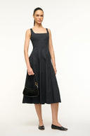 model wearing black sleeveless midi dress with black ballet flats and a black handbag