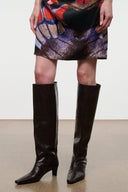 Knee-high heeled boot in dark espresso brown snake-embossed leather, sleek silhouette.