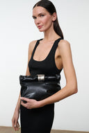 Black snake-textured cuff clutch with silver bar closure, held in hands