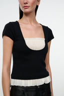 Black knit top with scoop neckline and ivory ruffled trim at hem