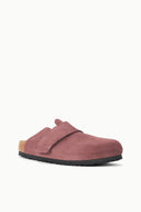 A single slip-on clog-style shoe in dusty rose pink suede, featuring a black outsole and a natural cork heel insert, shown against a plain white background.
