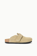 A single beige suede clog shoe with a hook-and-loop strap closure, a cork-look midsole, and a black outsole, shown in profile against a solid white background.