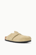 A light beige suede clog-style slip-on shoe with a black sole, shown from a side profile against a plain white background.