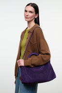Amethyst purple suede satchel with top handle and shoulder strap, worn on arm