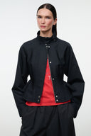 Black snap-front jacket with stand collar, peplum hem, and visible red inner layer