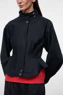 Black jacket with stand collar and snap details, peplum shape over a red top