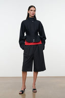 Black cropped jacket with stand collar, snap front, peplum hem over shorts