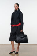 Black jacket with stand collar and snap front, worn with a black tote bag