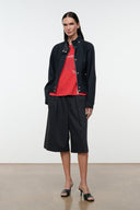 Black stand-collar jacket with snap front, worn open over a red top