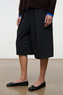 Black flat ballet shoes on model, pointed toe with bow accent