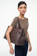 Brown tote bag with front buckle, top handles, and zippered side pocket
