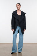 Black open-front jacket with relaxed lapels and buttoned shoulder straps