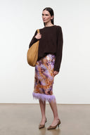 Galaxy print midi pencil skirt with lavender feathered hem, model standing with bag