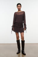 Dark brown sheer long-sleeve mini dress with ruched waist and tie-cuff sleeves, front view.