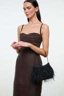 Black mini handbag with long fringe trim and thin shoulder strap, held by model.
