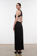 A woman modeling a floor-length black dress with a dramatic open back and halter-style shoulder straps, shown from the back in a studio setting.