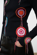 Black long-sleeve top with large circular embroidery and long hanging tassels