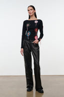 Black long-sleeve top with circular embroidered patches and tassel fringe