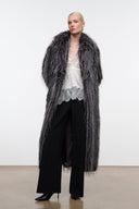 Black snake-print ankle boots with pointed toe and low heel under long coat