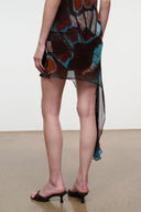 Short asymmetrical mini skirt with sheer side drape; dark teal and orange butterfly print.