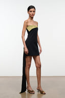 Strapless black mini dress with olive-gold diagonal overlay and long side drape