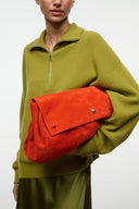 Oversized tangerine-orange flap bag with magnetic closure and short padded handle.