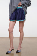 Dark navy sleep shorts with teal waistband and turquoise trim, hand holding hem