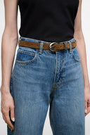 Brown suede belt with silver buckle over blue denim jeans at the waist.