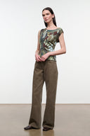Sleeveless butterfly-printed top in iridescent green and brown, worn with wide-leg pants
