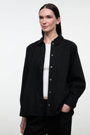 Black shirt jacket with stand collar, button front, and long sleeves; front view.