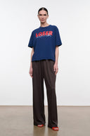 Blue relaxed tee with red 'LOSER' logo, styled with dark wide-leg pants