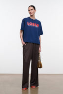 Blue relaxed tee with red 'LOSER' logo, worn with dark wide-leg pants