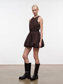 Front view of dark brown sleeveless mini dress with high neckline and pleated flared skirt