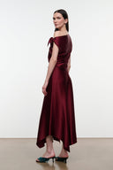 Deep burgundy silk midi dress with off-shoulder draped bodice and flowing asymmetrical hem