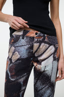Flare jeans detail: abstract butterfly print with orange and gray swirls, dark base