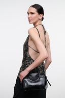 Black mini carryall crossbody bag with circular textured medallion and side tassel