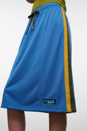 Blue midi skirt with olive waistband, side stripe, drawstring; small logo patch at hem.