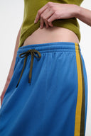 Blue midi skirt with elastic waistband, drawstring tie, olive border stripe; side view.