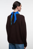 Brown knit sweater with blue-green scarf tied at back yoke