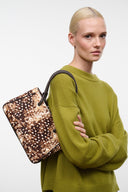 FIONA shoulder bag held by model, fawn speckled haircalf with braided handles