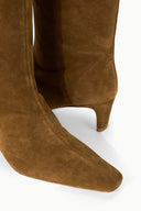 Cigar brown suede knee-high boot close-up showing heel and smooth toe