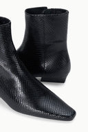 Black snake-embossed flat ankle boot inner-side view at ankle and heel