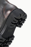 Zip ankle boot outsole view with thick black lug tread and embossed brand mark