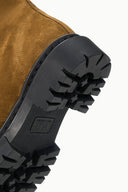 Chunky black lug outsole with deep ridged tread on cigar-brown ankle boot