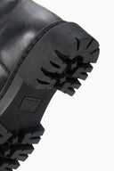 Black boot outsole tread detail with ribbed pattern and deep lugs