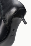Black ankle boot close-up showing side zipper and smooth pointed toe