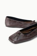 Pair of espresso brown ballet flats with stitched trim and bow ties, close-up view.