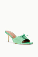 Seafoam suede slide mule with open toe, tied lace bow, and narrow stiletto heel