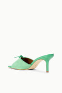 Seafoam suede mule slide with open toe, tied lace bow, and slim high heel