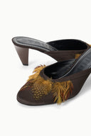 Espresso brown mule close-up with gold feather-trim, curved topline, and dark lining